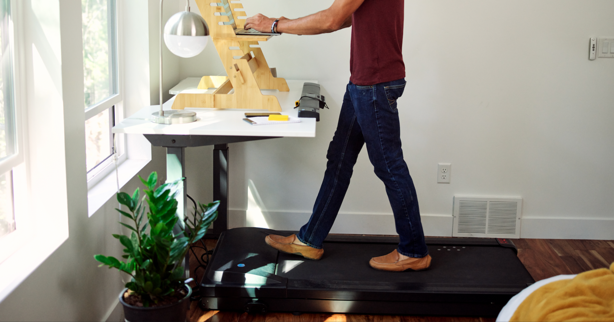 A man in his home office using a walking pad whilst typing